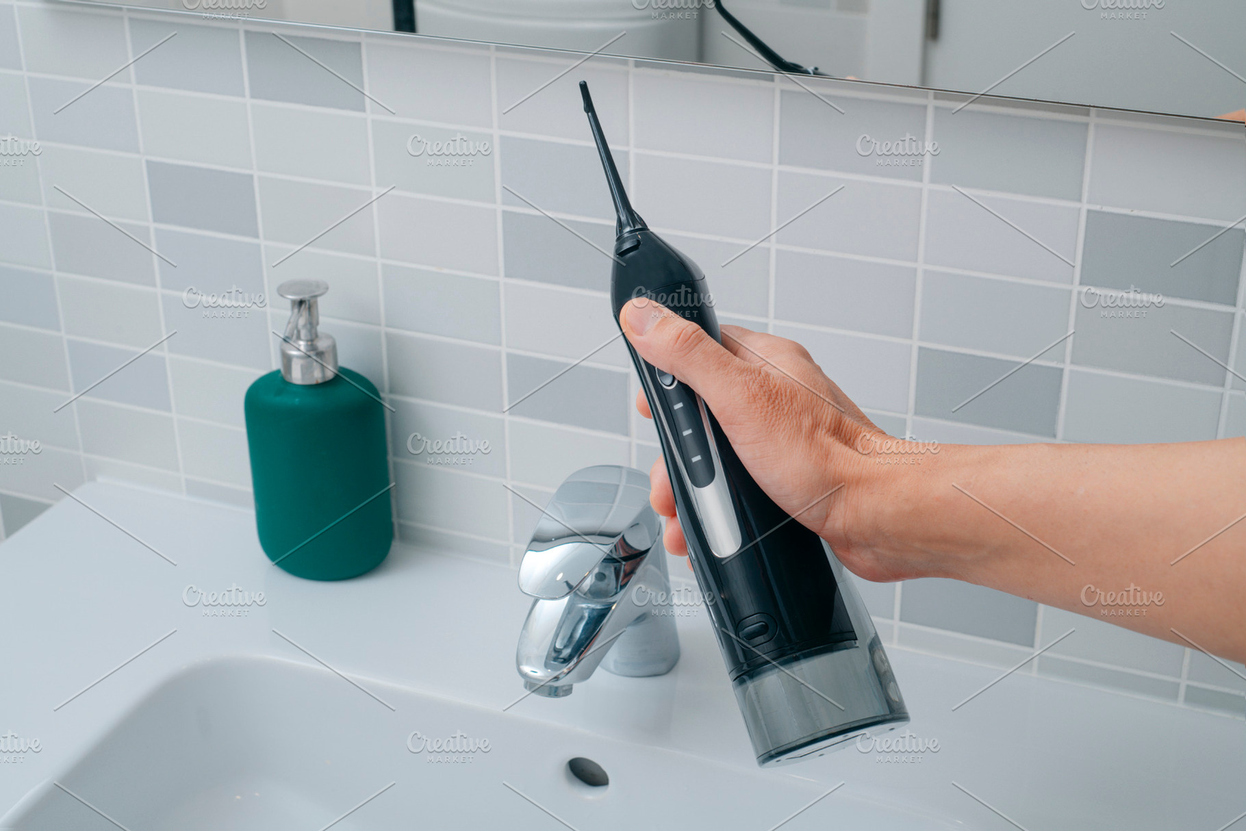 a man holding an oral irrigator in the bathroom, a Photo by Nito