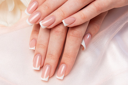 Woman showing french manicure and diamond ring near orchid flowe