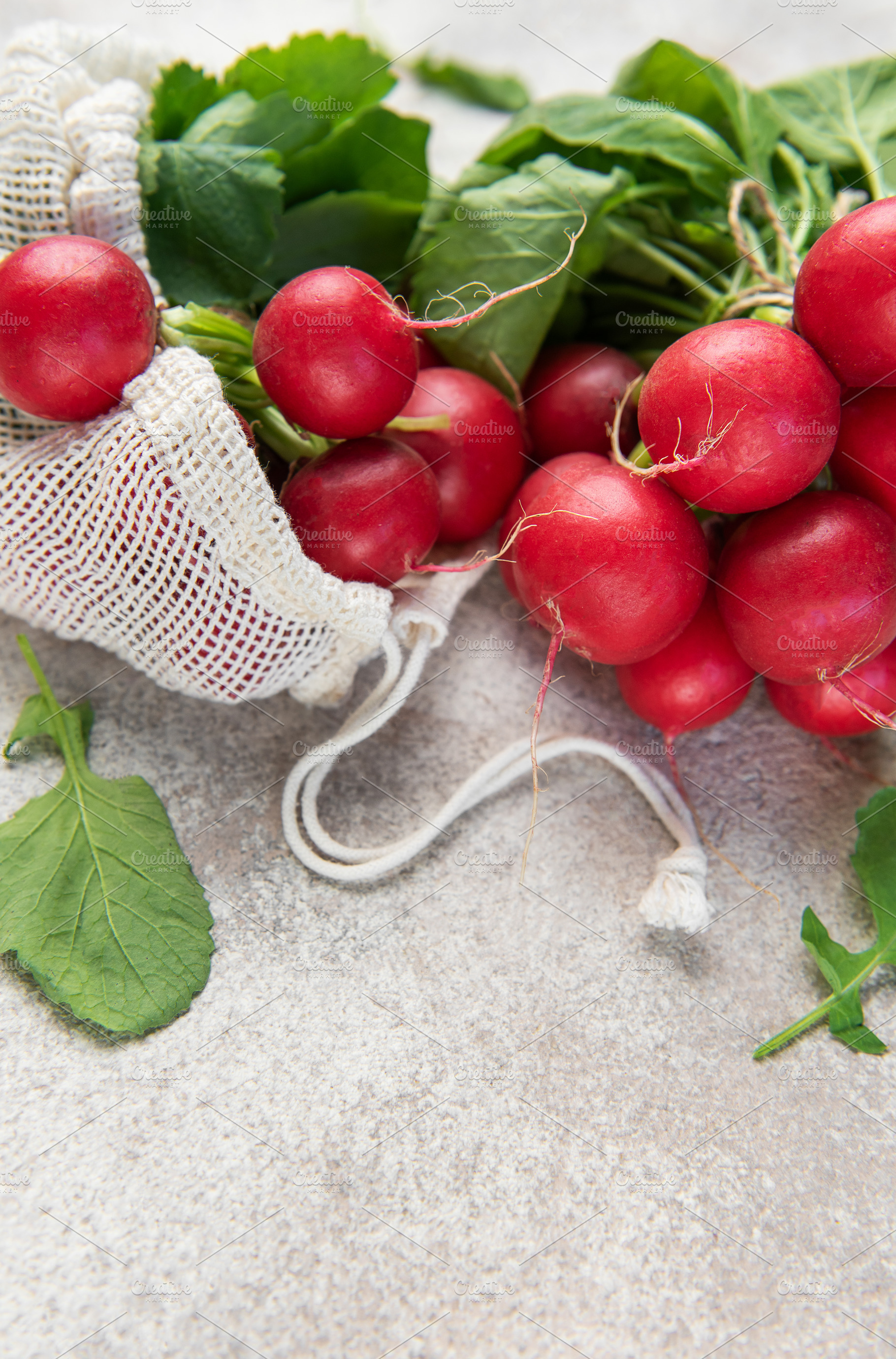 Fresh red radishes with green leaves in a reusable mesh bag, a Food & Drink Photo by Olena Rudo