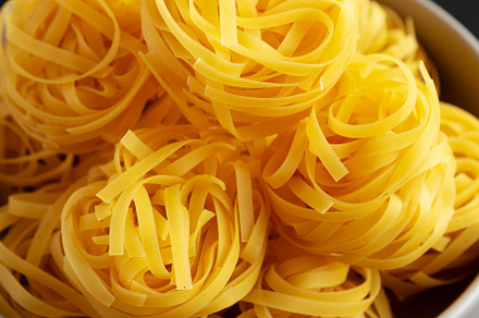 Raw Dry Tagliatelle Pasta in a Bowl, side view., a Food & Drink Photo by LiudmylaChuhunova
