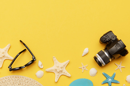 Summer holiday accessories lying on vibrant yellow background wi