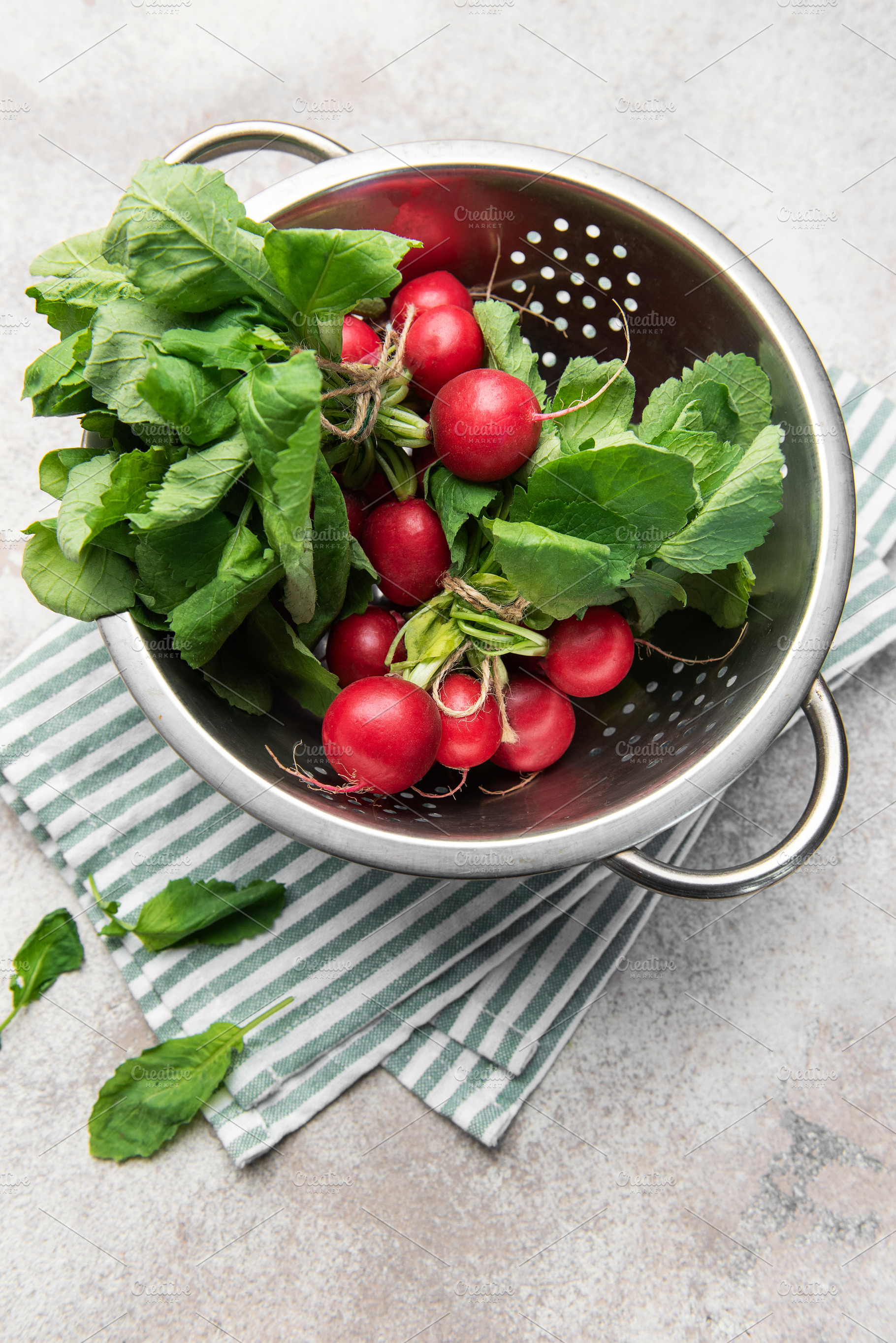 Fresh radishes with green tops in colander, a Food & Drink Photo by Olena Rudo