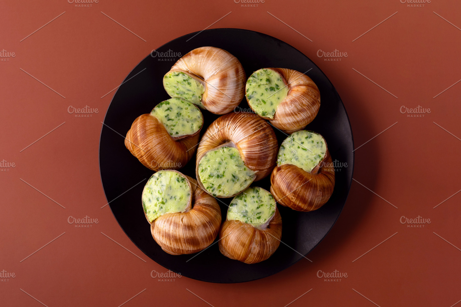 Top view of cooked escargot with garlic herb butter on a black p, a Food & Drink Photo by Ales Munt