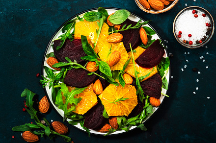 Beet Salad with orange, arugula and almonds on blue table backgr, a Food & Drink Photo by 5PH