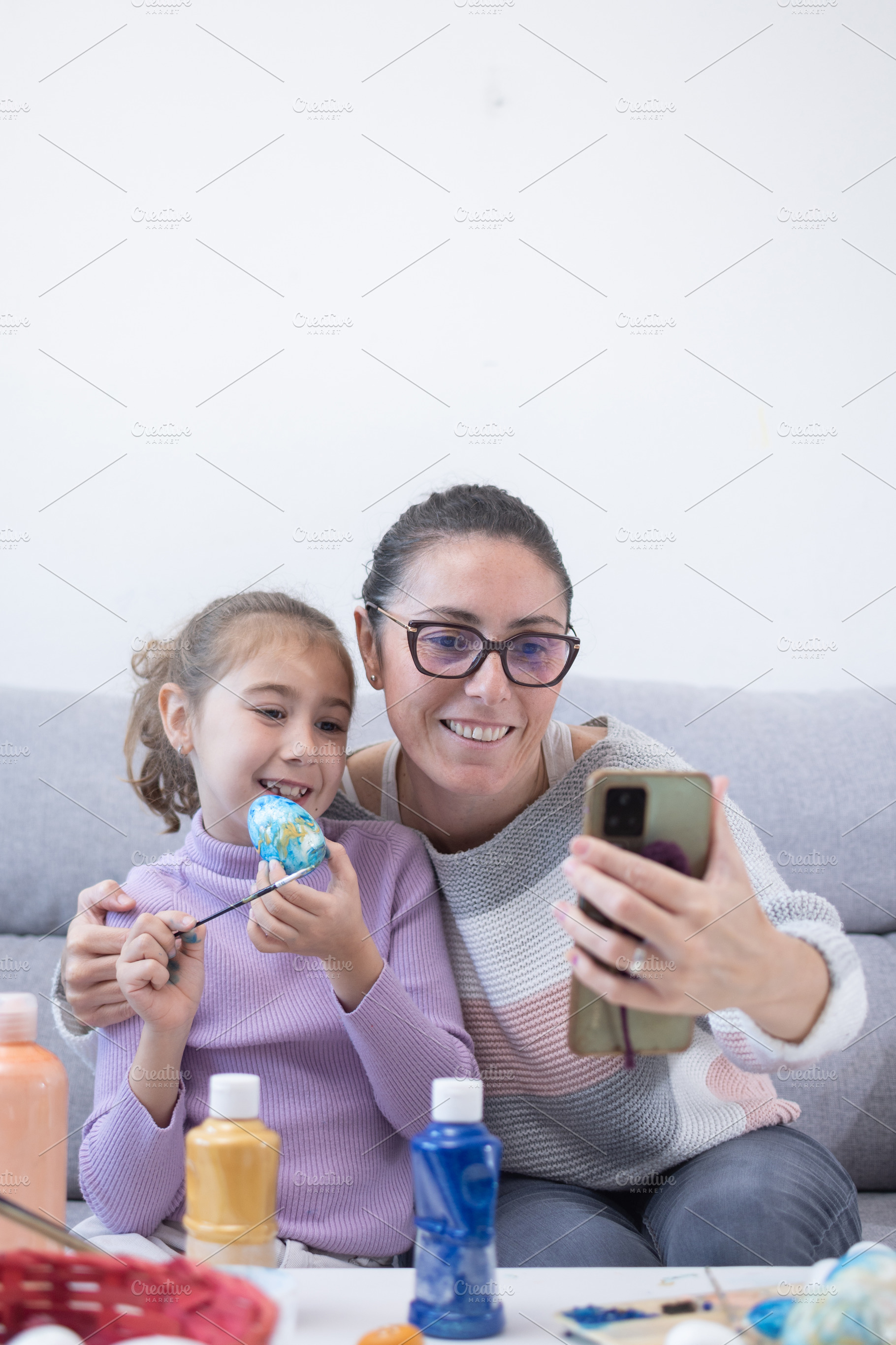 Mother and daughter taking a selfie while decorating Easter eggs at home, a Food & Drink Photo by etorres69