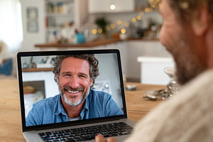 Therapy session in progress with a smiling man on a virtual call in a cozy home, a Technology Photo by AlyaAnd