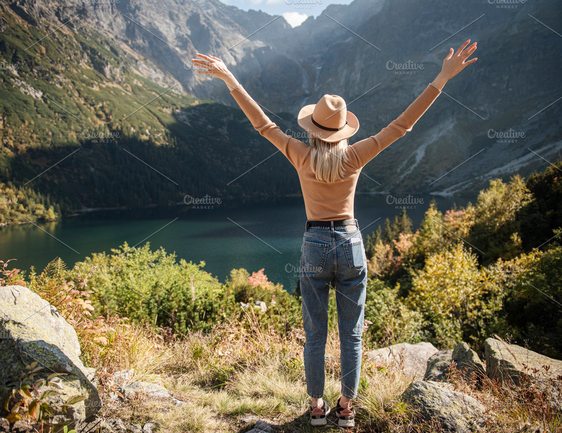 Young tourist woman in a hat with hands up on the top of the mou, a Sports & Recreation Photo by Olena Rudo