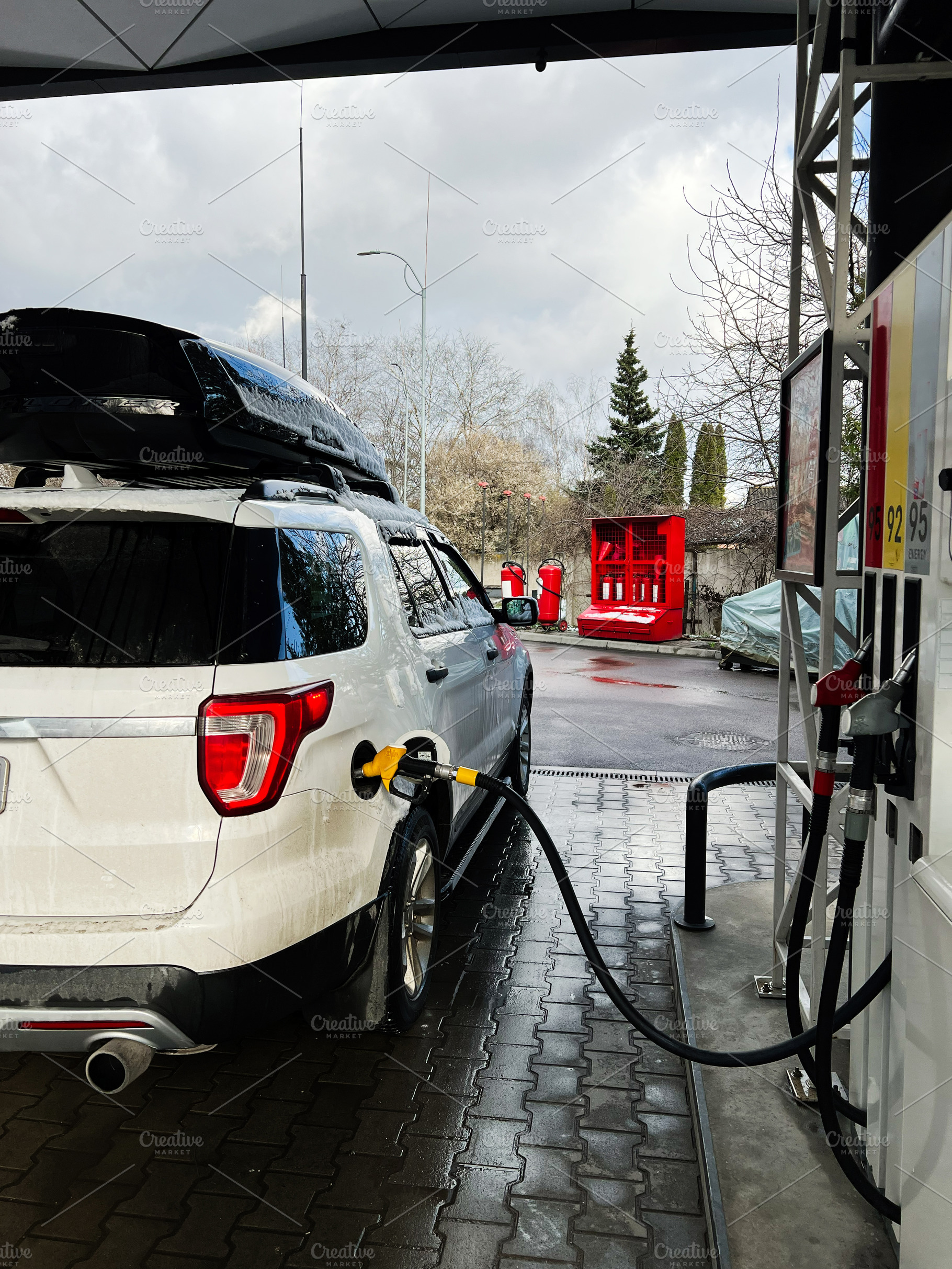White vehicle refueling at a gas station during a cloudy day, a Photo by AS photostudio