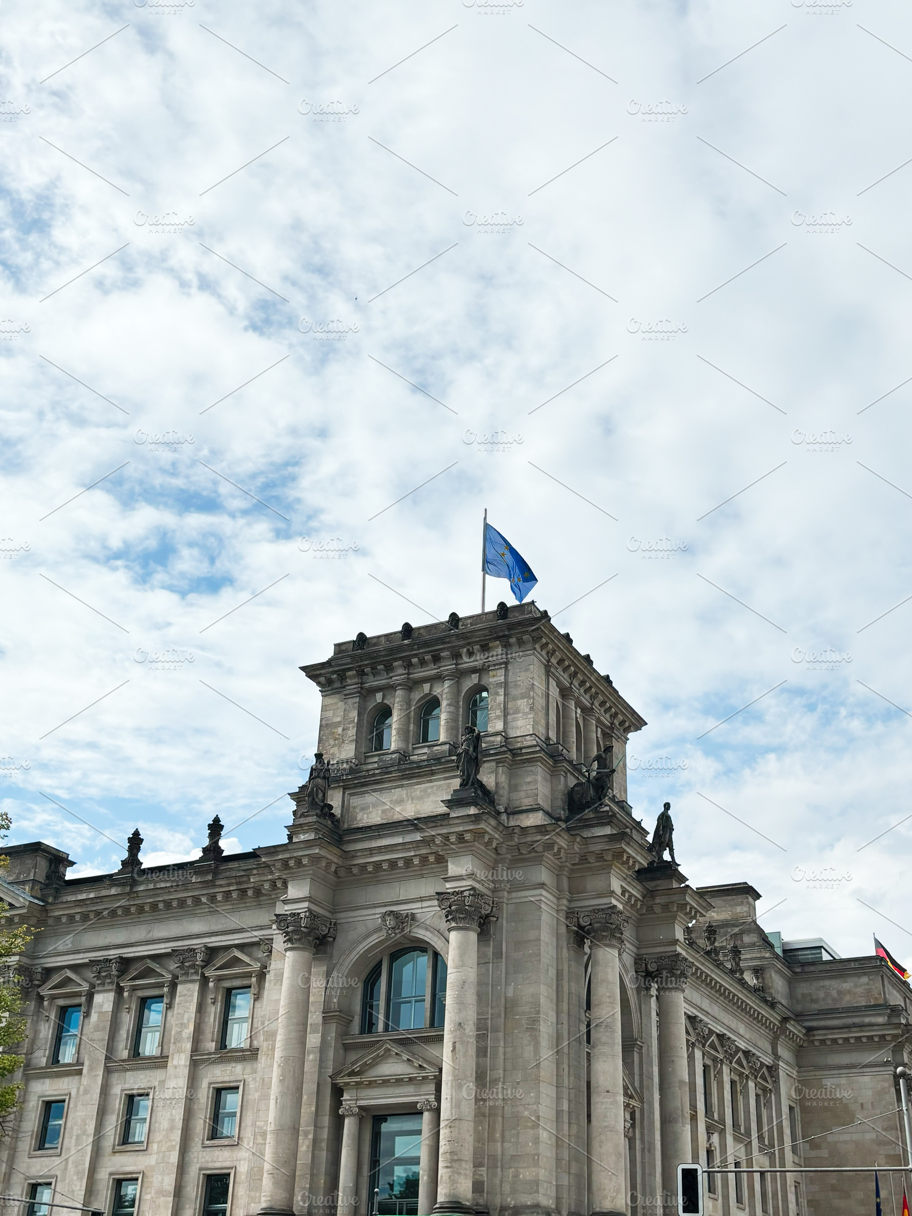 Historic government Reichstag building with European flag under cloudy sky, a Photo by AS photostudio