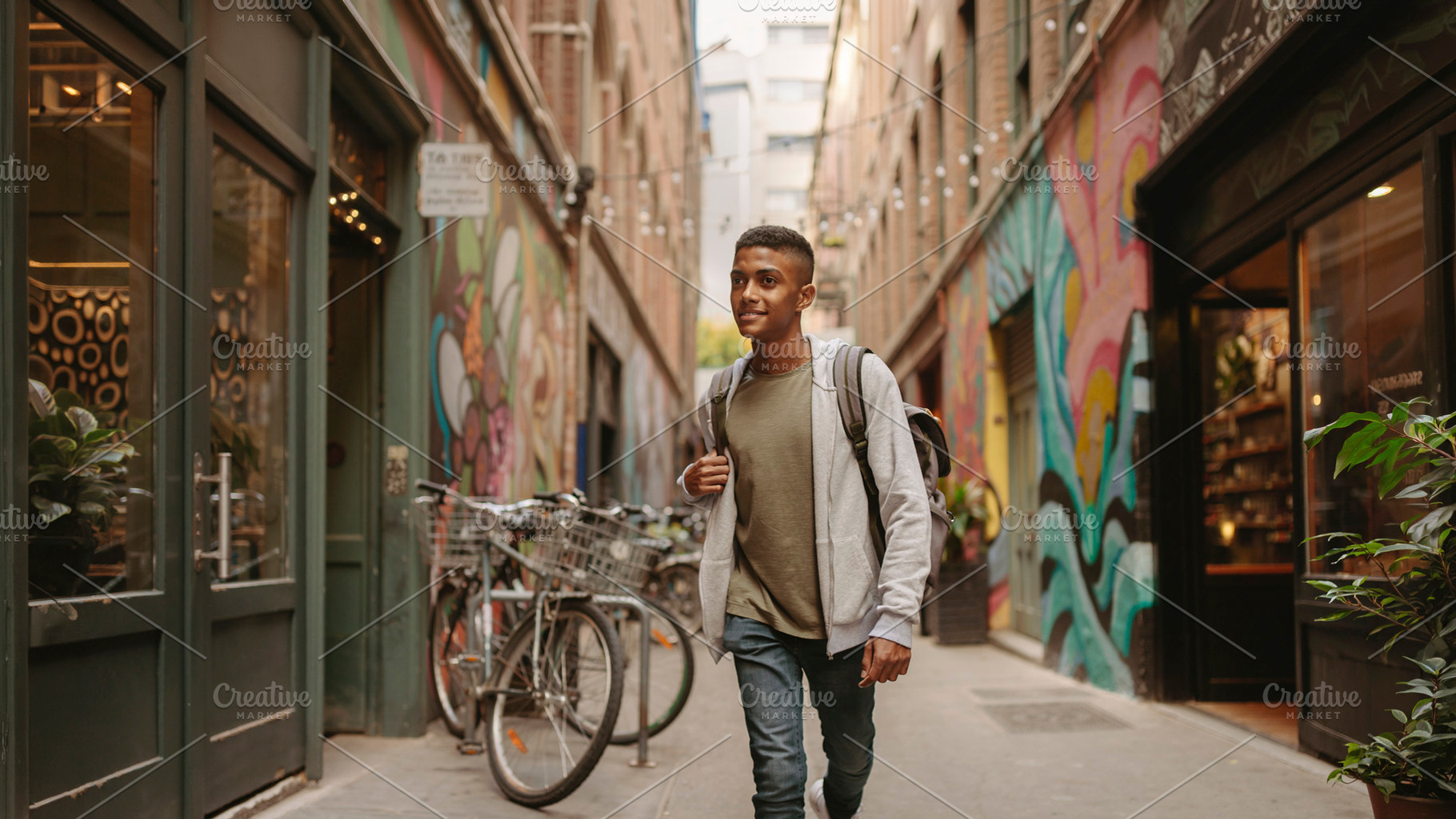 Black teenager walking through colorful downtown alley, a Person Photo by DanFLCreativo
