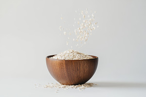 Oats falling from a wooden bowl in a, a Photo by Tanuart
