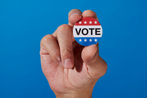 a close-up of a vote badge held by a man