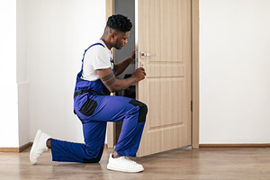 African American Male Worker Installing New Door In Apartment Indoor, a Photo by Prostock-Studio