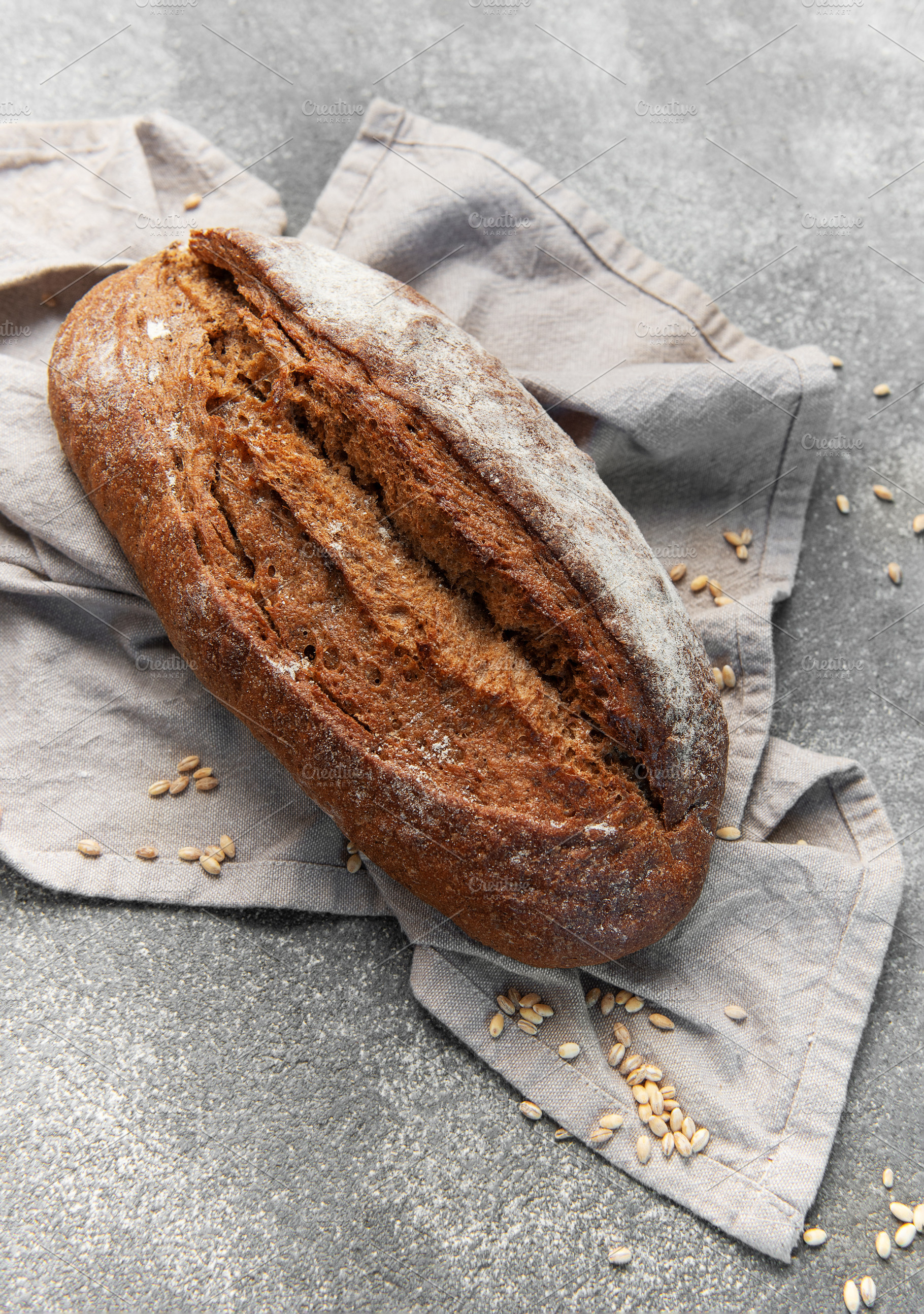 Rustic rye sourdough bread loaf on gray cloth, a Food & Drink Photo by Olena Rudo