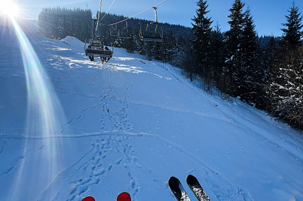 Skiers riding a ski lift on a sunny winter day in a snowy forest, a Photo by AS photostudio