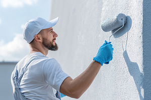 Painter man painting the wall using paint roller, an Industrial Photo by AlyaAnd