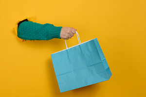 A woman's hand, clad in a green knitted sweater, holds a blue pa, a Person Photo by ndanko
