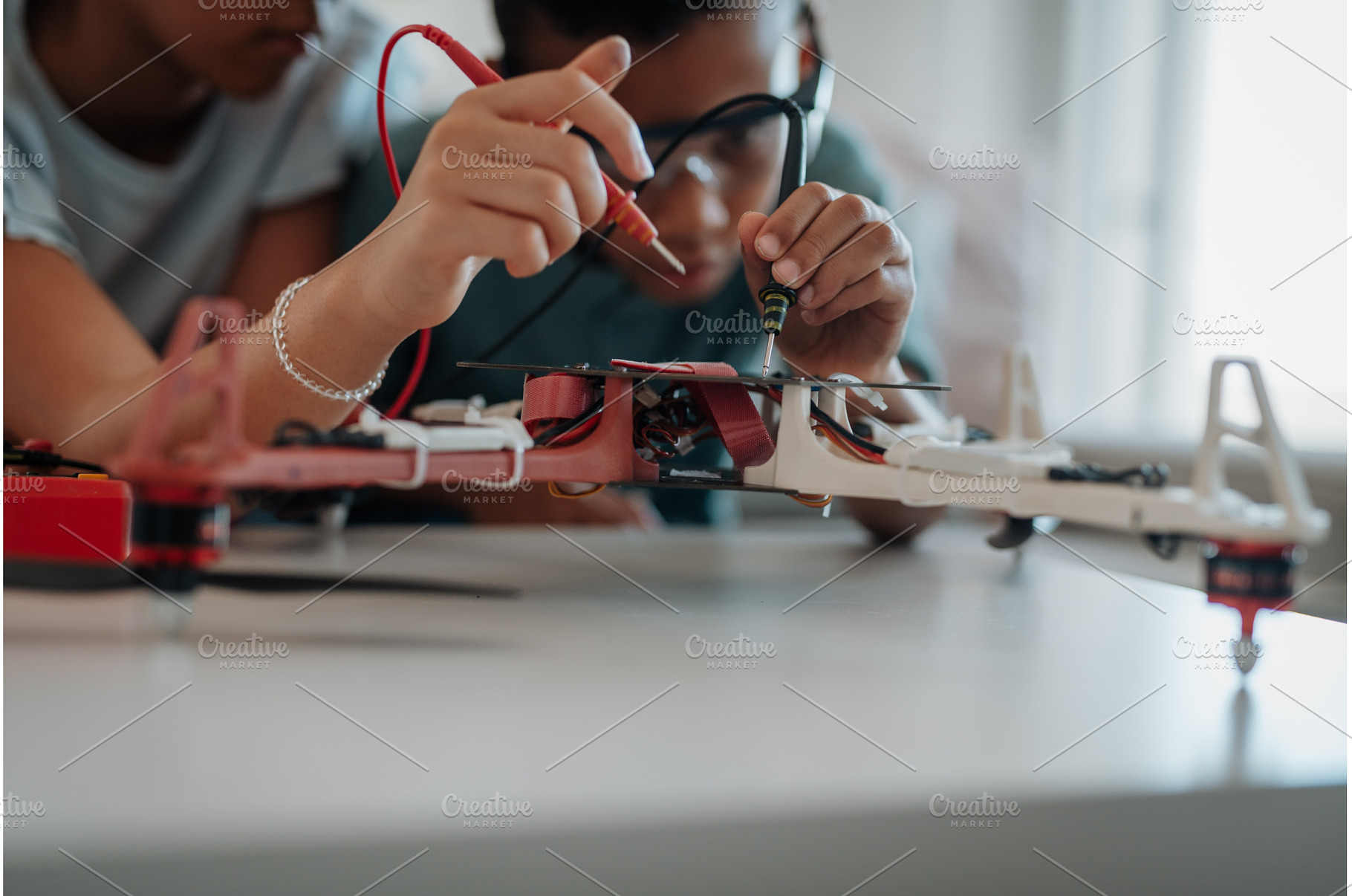 Classmates assembling robotic kit, a School & Education Photo by HalfPoint