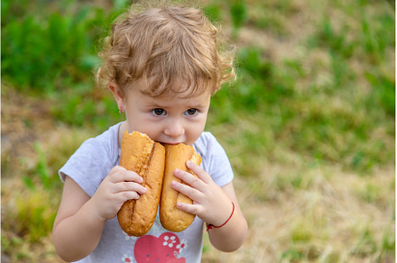 A child eats bread in the park, a Person Photo by yanadjana