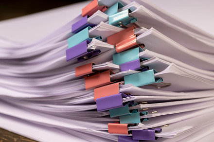 sheets of paper are connected by multicolored clips, stacked sheets of paper fo