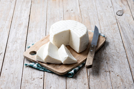 Sliced fresh white cheese from cow's milk on wooden table, a Food & Drink Photo by etorres69
