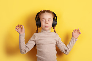 Calm young girl with headphones enjoying music, eyes closed, yel, a Person Photo by Ales Munt