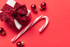 Christmas gift box, candy cane, and ornaments on red background, a Holiday Photo by Olena Rudo