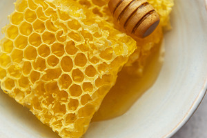 Honeycomb and honey dipper resting in bowl on table, a Food & Drink Photo by Olena Rudo