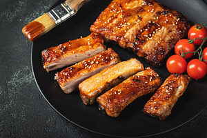 Hot grilled spare ribs from a summer BBQ served on a plate with sauce. Top view, a Food & Drink Photo by Budarinphoto