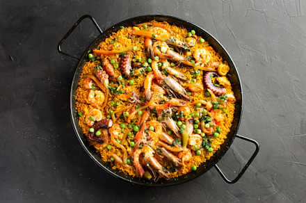 Paella served in paella pan on black