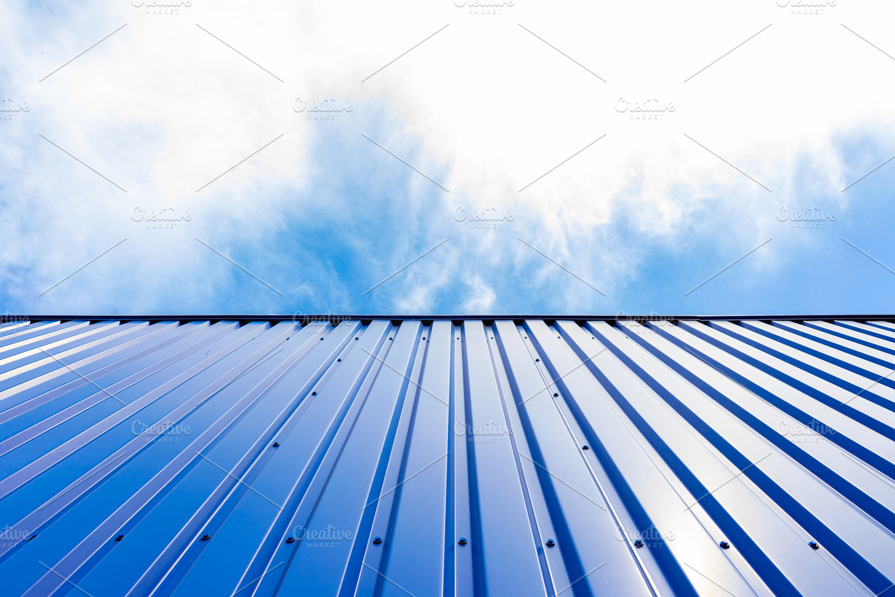 Low-angle view of a blue corrugated metal wall against a bright, a Background Photo by Ales Munt
