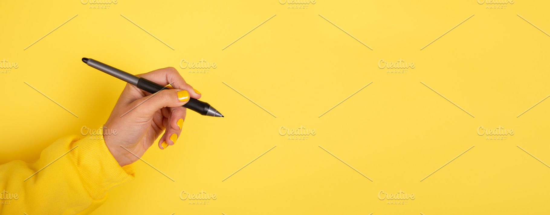 Female hand holding a black pen against a vibrant yellow backgro, a Business Photo by Ales Munt