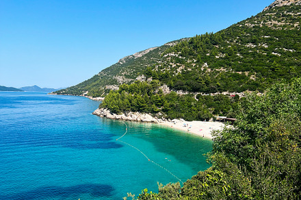 Idyllic beach with clear blue water and lush green hillside.  Beach Veliki Zal,, a Photo by AS photostudio