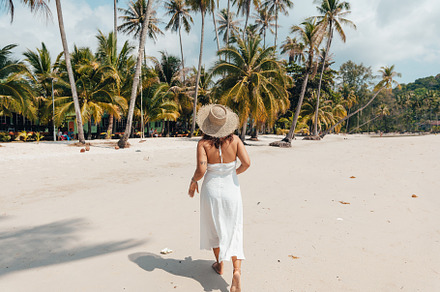 A woman in a hat enjoys the summer sun on a beautiful tropical b, a Holiday Photo by Art Rachen
