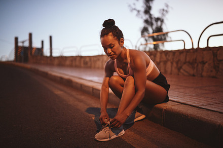 Fit young woman tying her running shoes before a run
