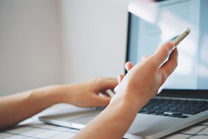 Hands using smartphone and laptop