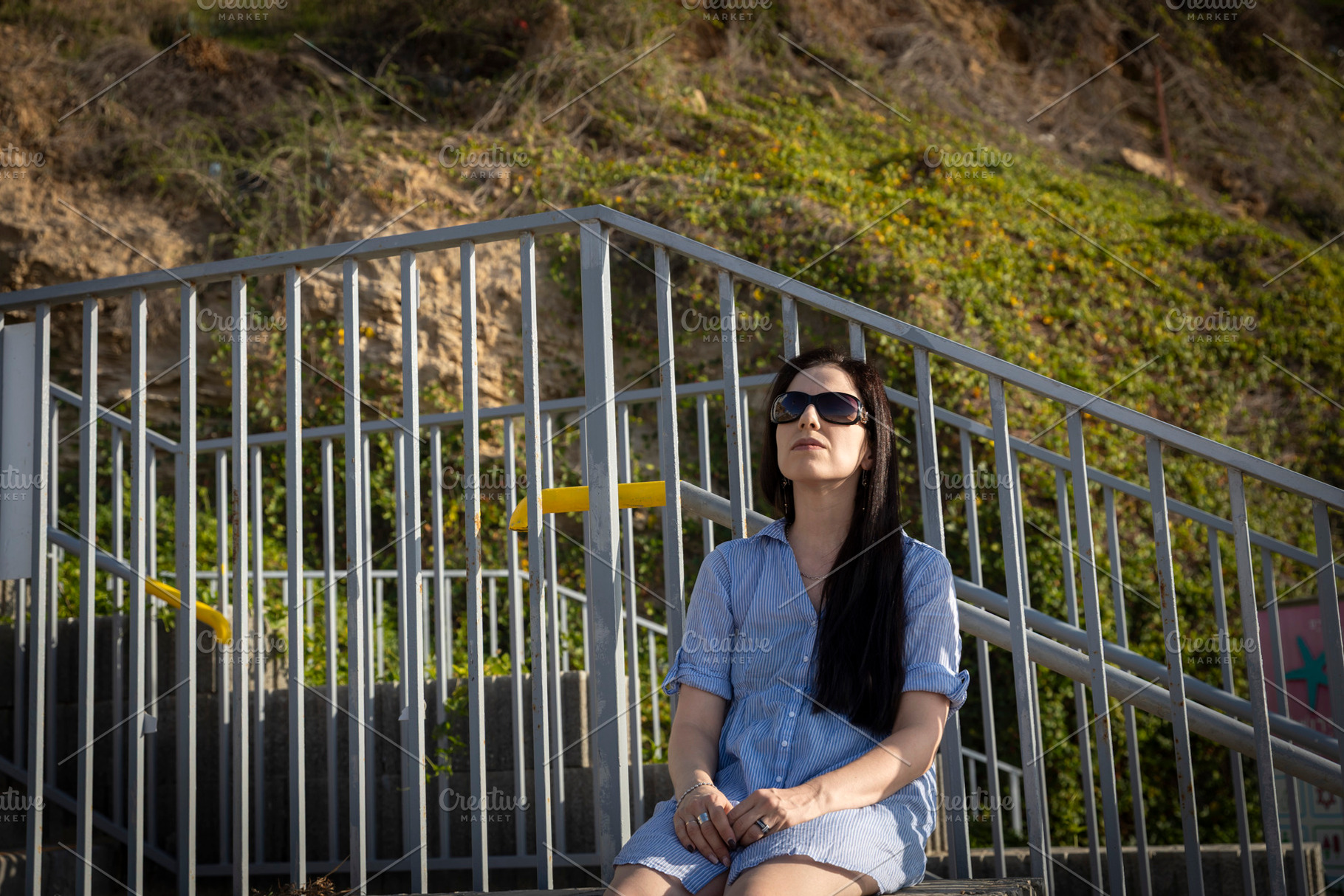 Woman in a light blue striped shirtdress sitting thoughtfully on, a Person Photo by Imaginarium