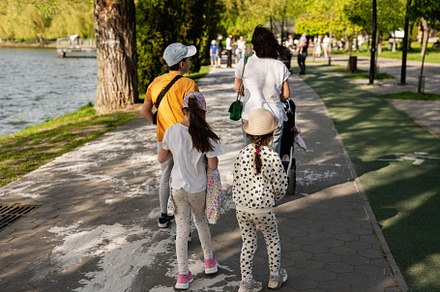 Family strolling by a river in a sunny park setting, a Person Photo by AS photostudio