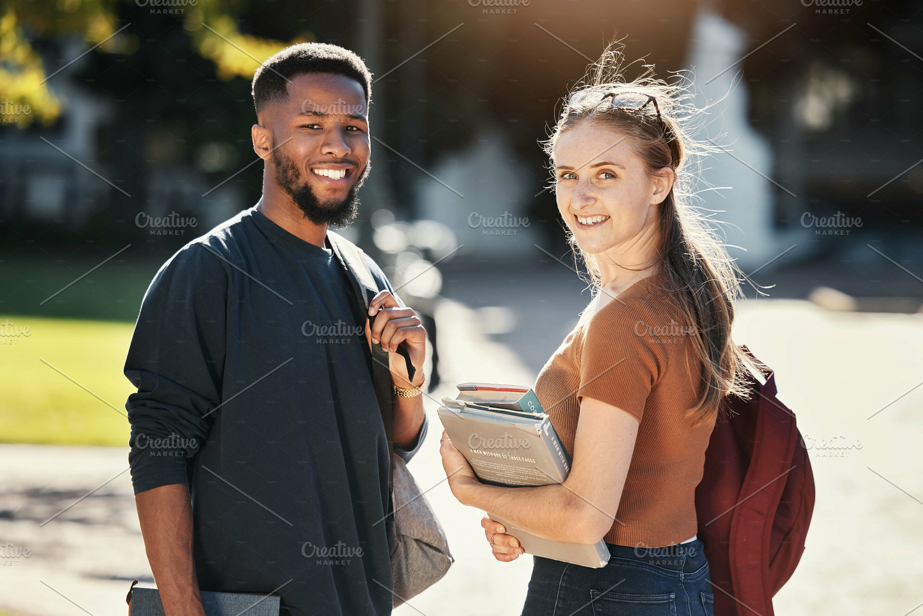 Students, couple or university friends walking together with books for education and learning on campus with scholarship. Portrait of an interracial man and woman together on college or school ground, a Photo by Peopleimages.com