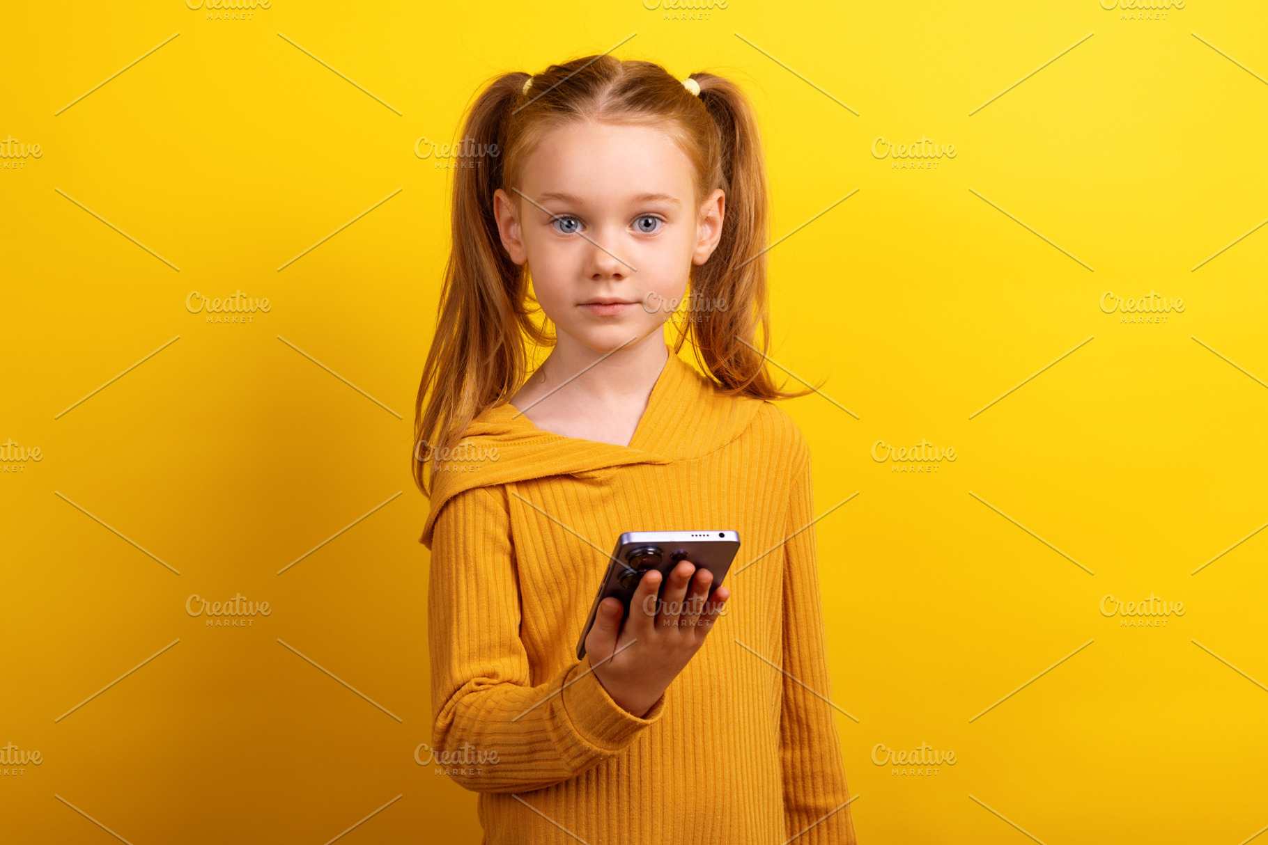 Young girl in a mustard sweater holding a smartphone and looking, a Person Photo by Ales Munt