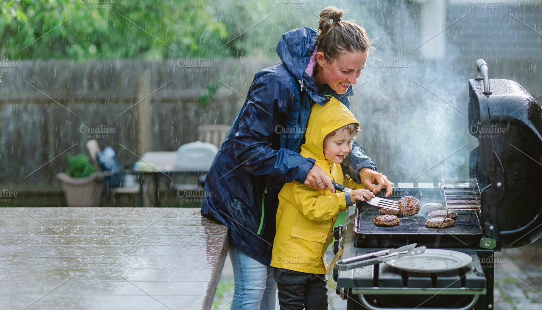 Mother and child cooking at rainy barbecue, a Person Photo by DanFLCreativo