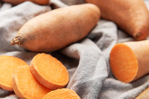 Raw sweet potatoes with sliced pieces and knife for cooking, a Food & Drink Photo by Olena Rudo