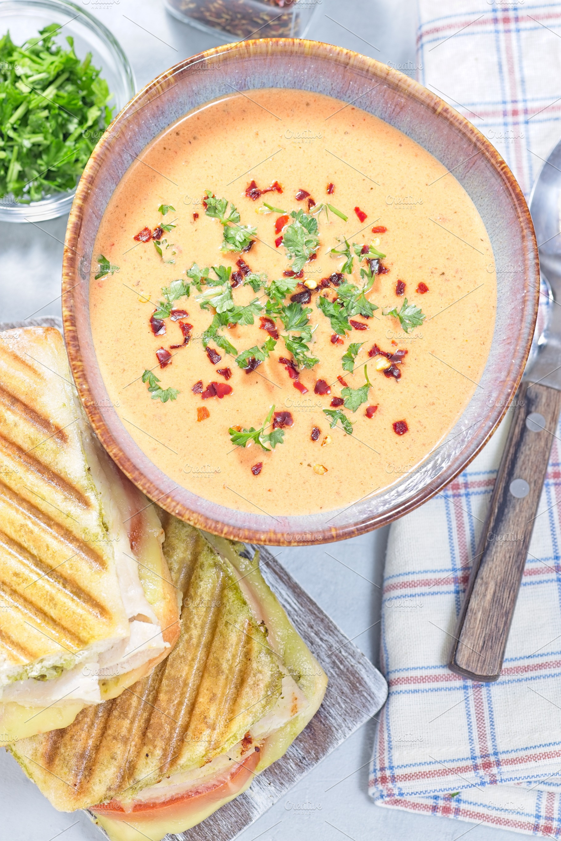 Red bell pepper cream soup served with grilled turkey panini, vertical top view, a Food & Drink Photo by iuliia_n