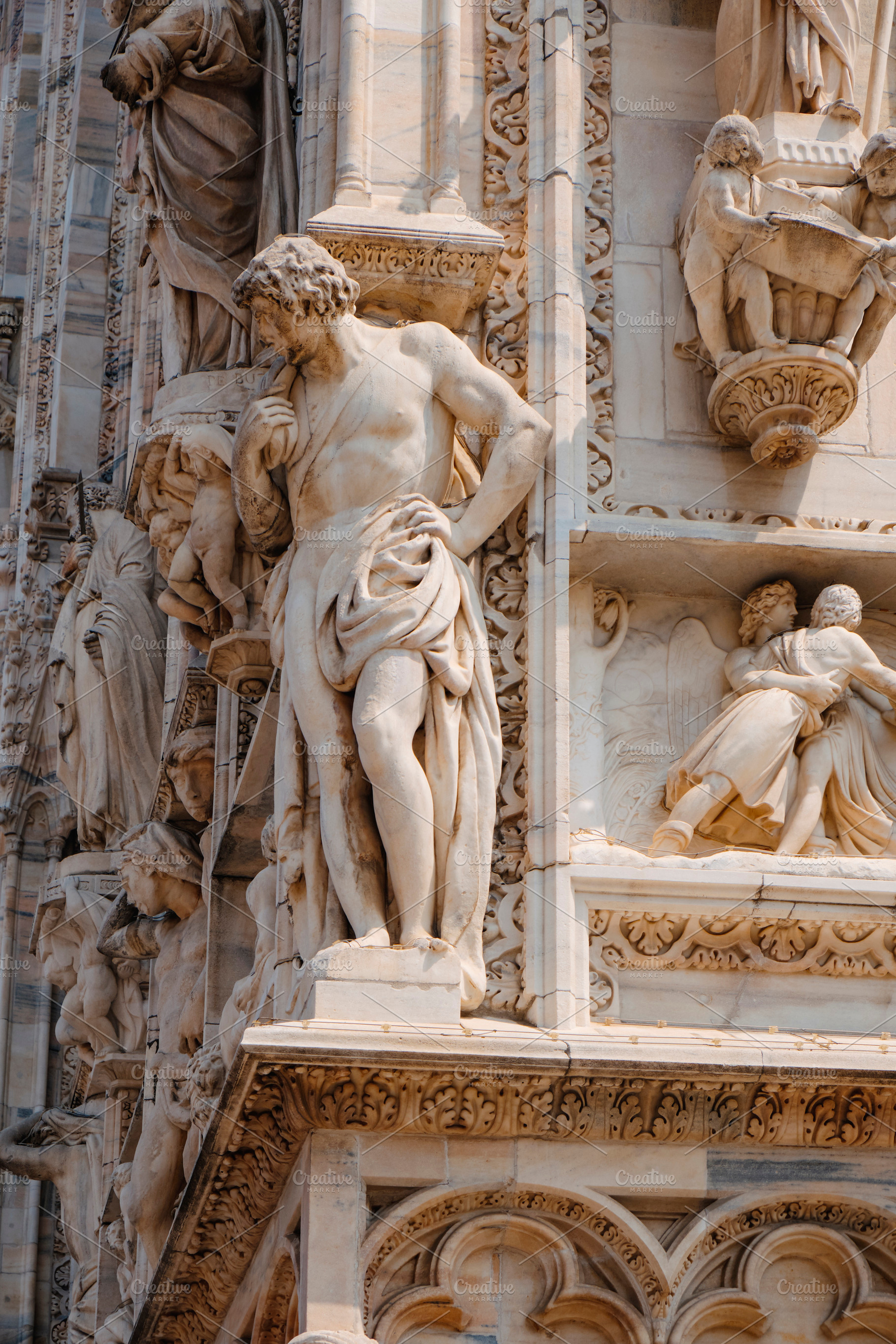 a figure leans on Milans Cathedral corner, a Photo by Nito