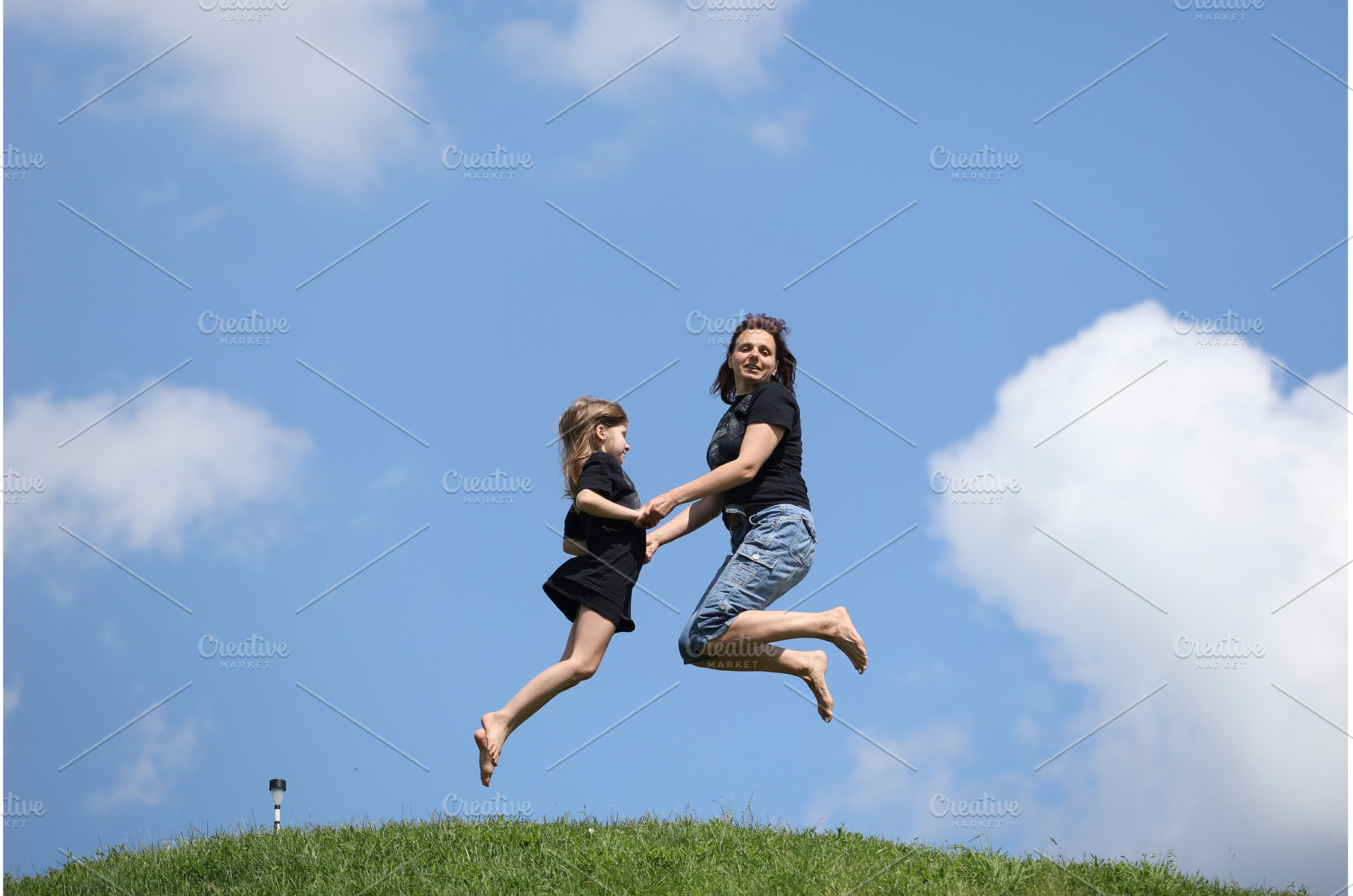 Mother and daughter happily jumping, a Nature Photo by Nenahliadava Design