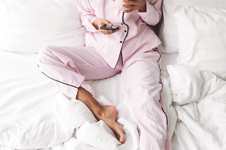 Lady with dark curly hair in stock photo containing blanket and pillows