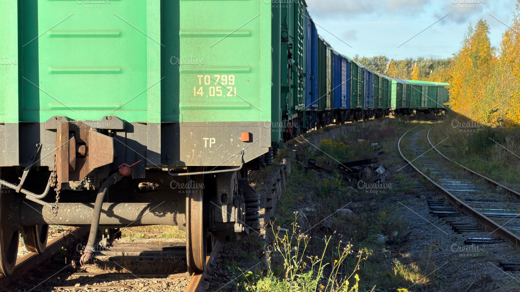 A close-up view of a green freight train car on tracks, with a long line of tra, an Industrial Photo by Textures & Backgrounds
