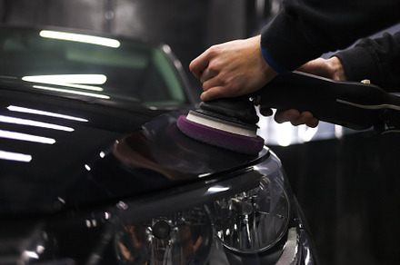Worker polishes a car’s paintwork, a Photo by borodai94
