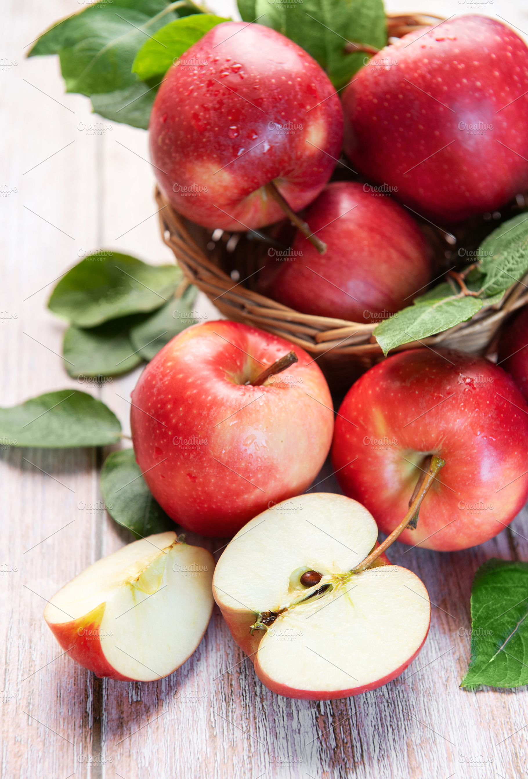 Red organic apples in basket with fresh green leaves, a Food & Drink Photo by Olena Rudo