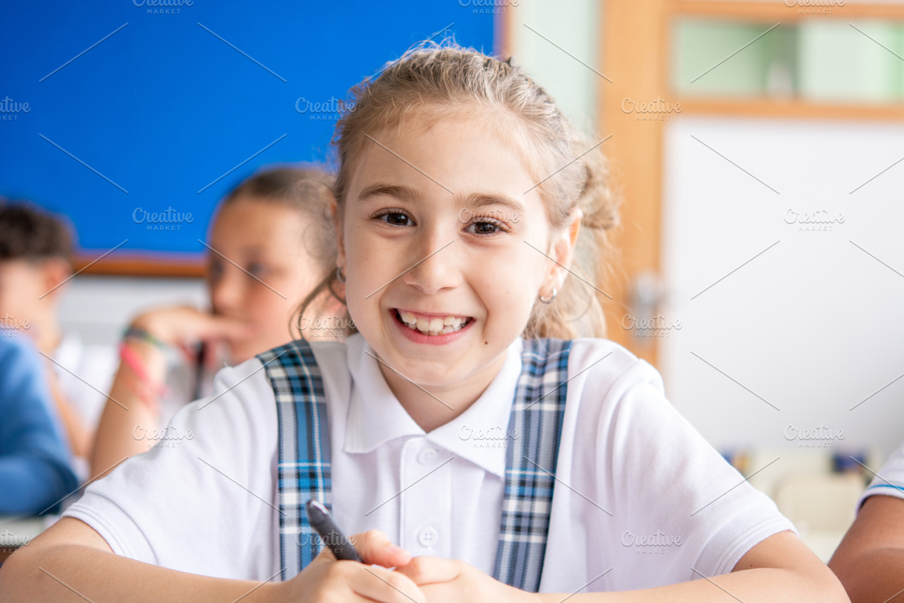 Smiling Elementary School Girl Sitting at Desk During Classroom Lesson, a School & Education Photo by etorres69